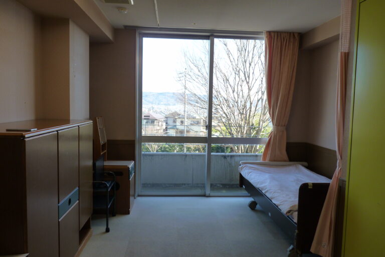 介護用ベッド、収納、大きな窓からの眺望がある居室